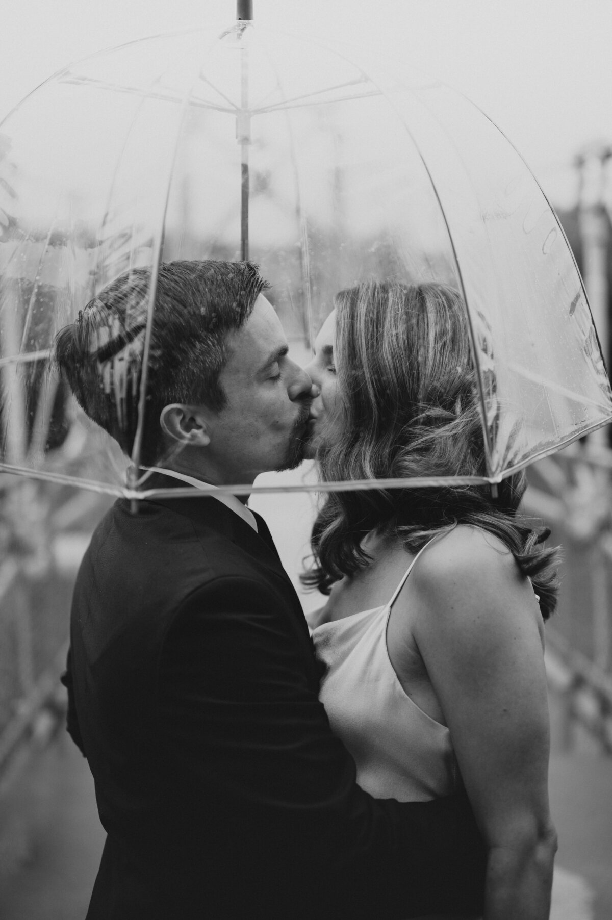 Couple kissing under a clear umbrella in the rain on their wedding day in Pennsylvania
