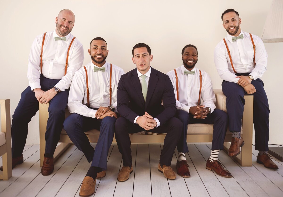 Groom with his groomsmen sitting on bench at wedding in Cancun