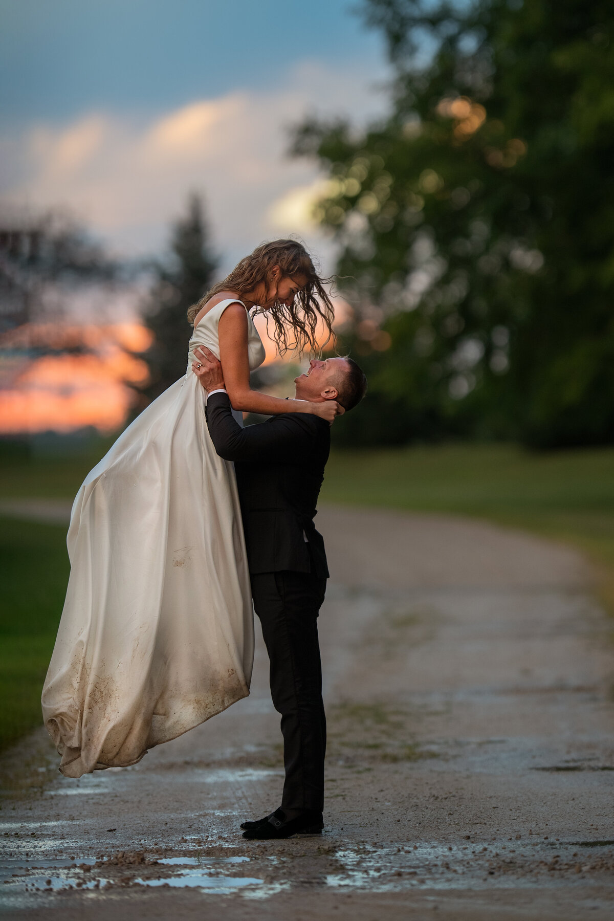 Happy newlyweds having fun in the rain on their wedding day during sunset