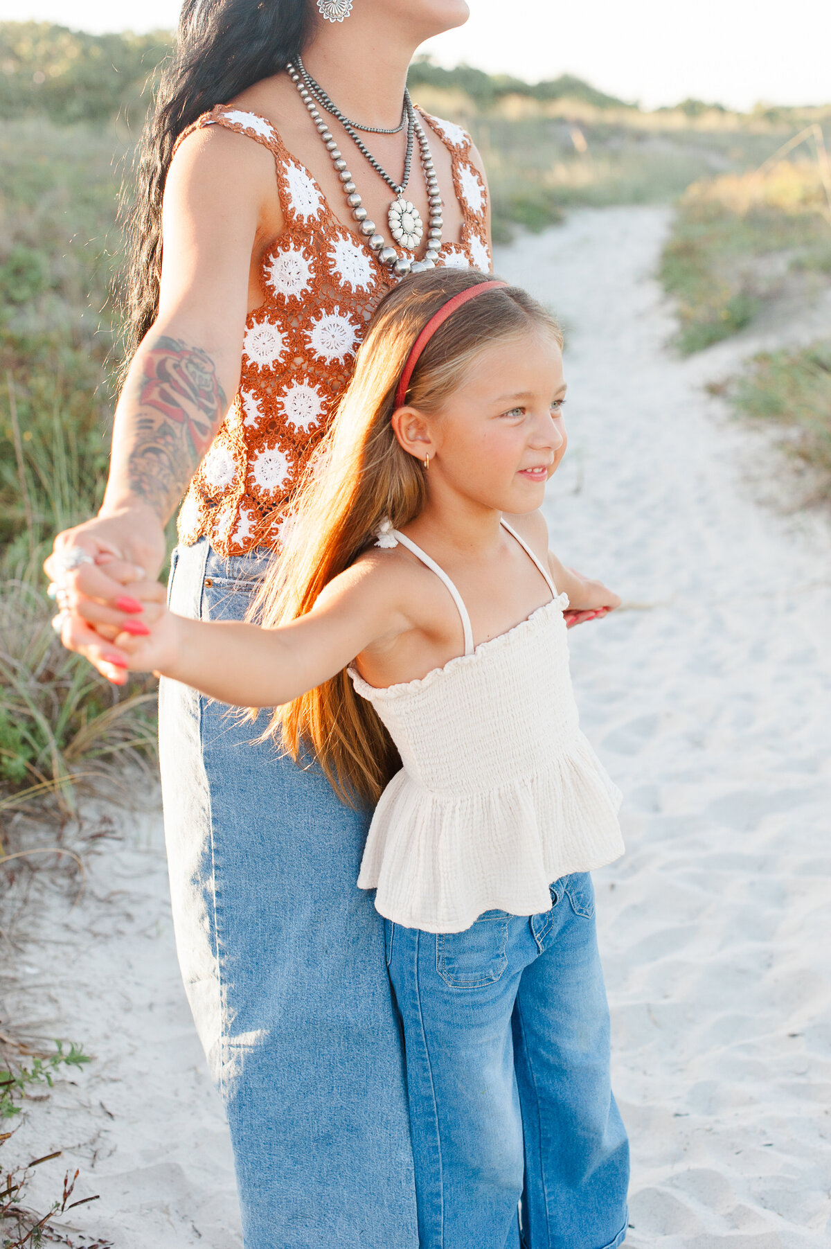 Mom holding daughters hands and dancing with her in the dunes