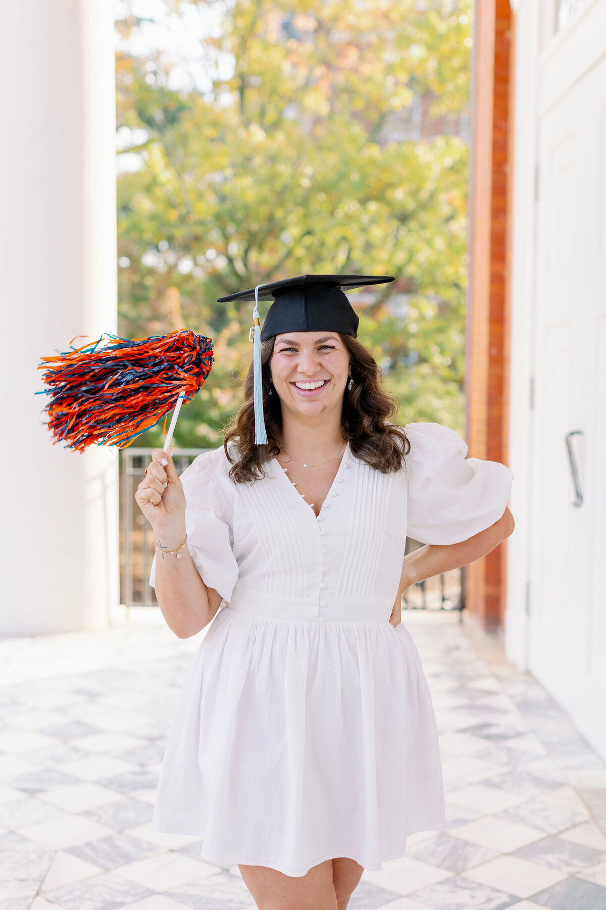 Auburn graduate smiling with cap and pom pom