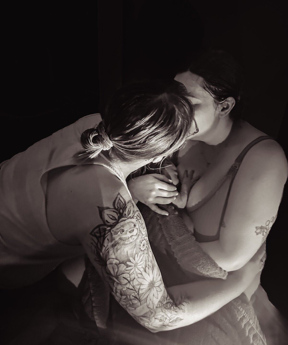 lesbian couple kisses after the birth of their child