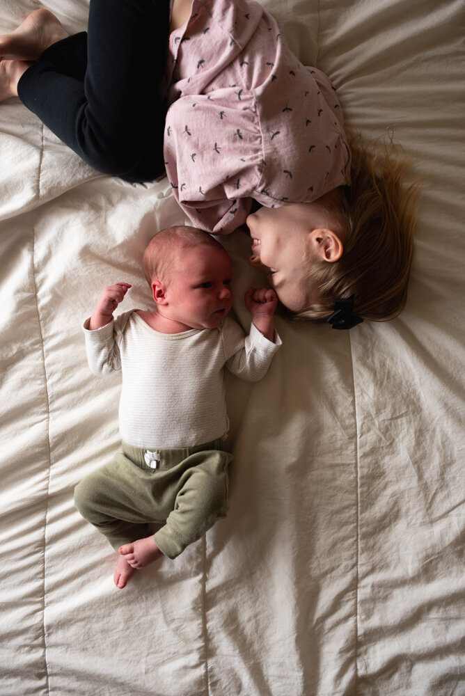 Siblings lying on bed touching noses