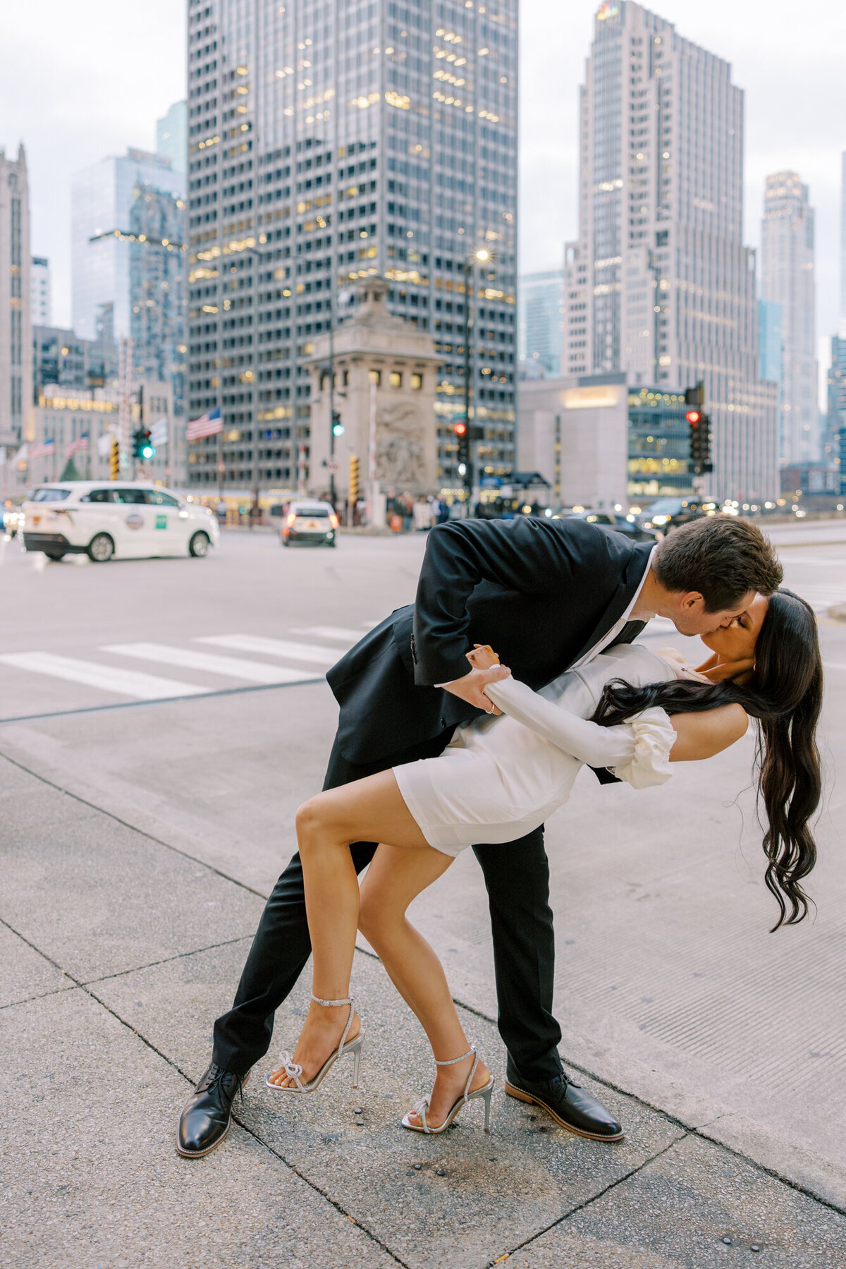 A couple embraces at dusk along Michigan Avenue and the Chicago River, with the city lights creating a romantic and timeless backdrop.