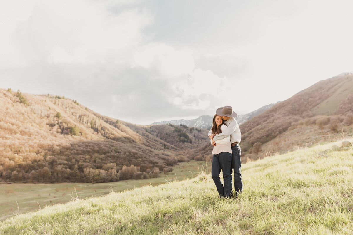 Taysie and Carter embrace on this hill for their engagements photos in preparation for their wedding which will take place in Benson, Utah and photographed by Robin Kunzler Photo