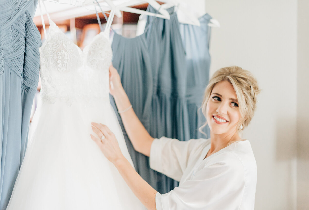 Bride holds up glamorous wedding dress while getting ready for luxurious outdoor wedding ceremony