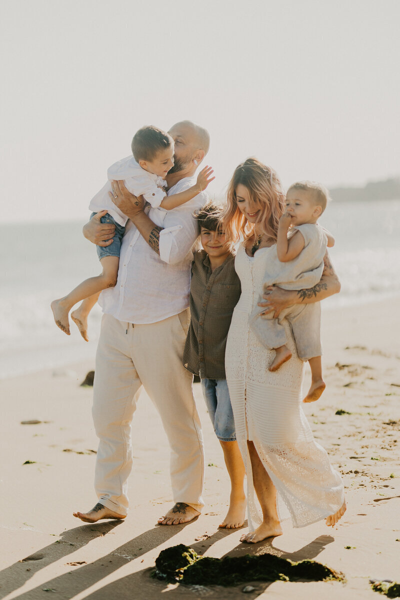 Famille avec trois enfants marchant côte à côté dans un décor de plage, immortalisée par Laura, photographe famille en Vendée.