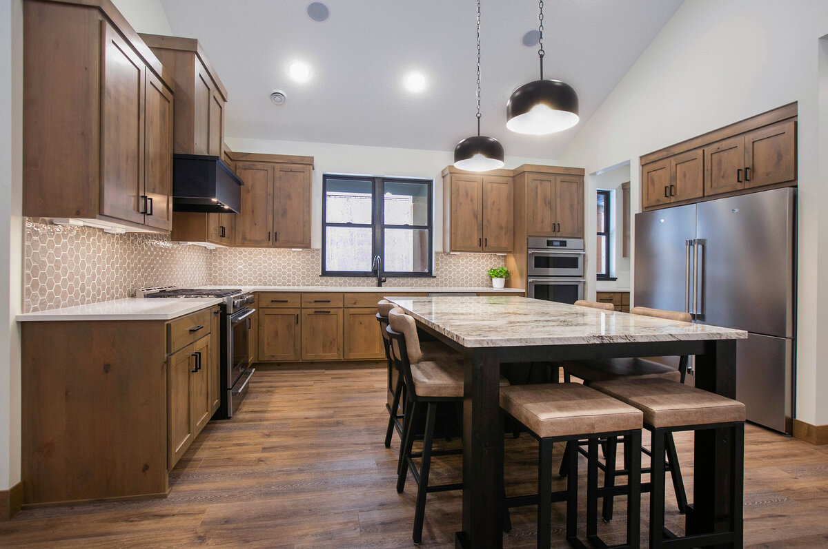 Open kitchen with dark cabinets, large island, and quartz countertops in an Elk River custom home