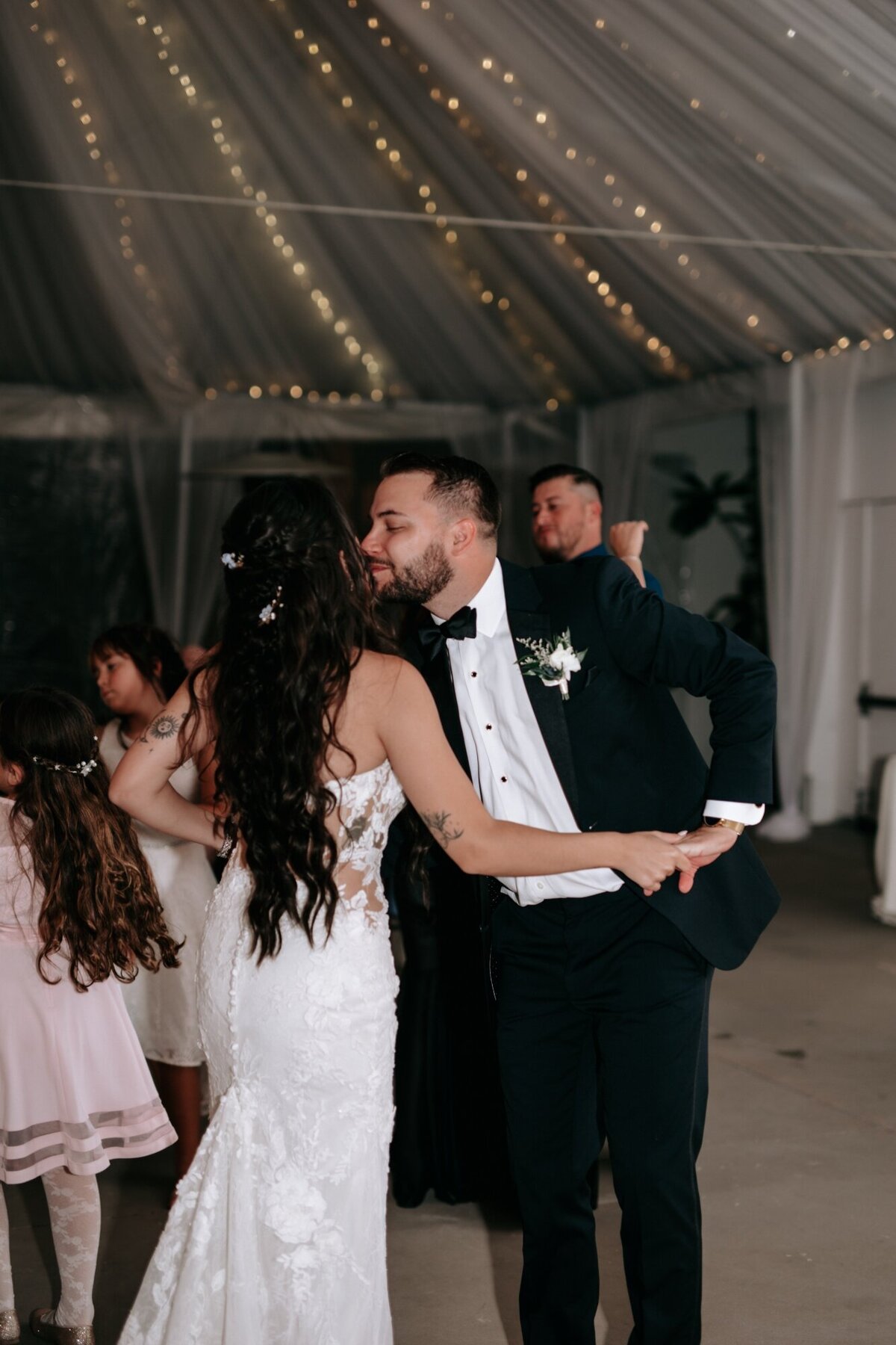 Groom kissing the bride on the cheek while dancing during reception.