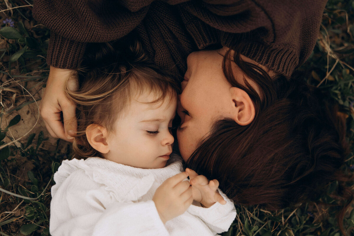 mother and child having a tender moment lying in the grass