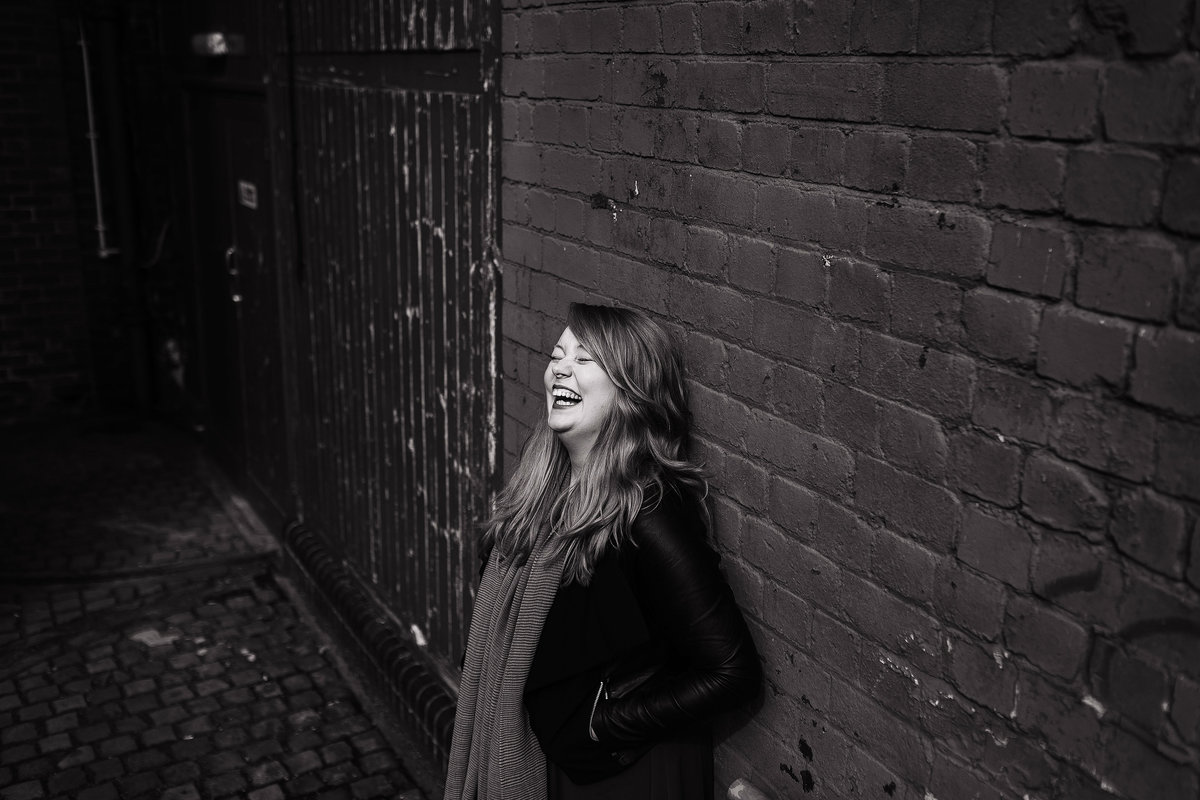 A black and white photo of a girl laughing during their pre wedding photo shoot