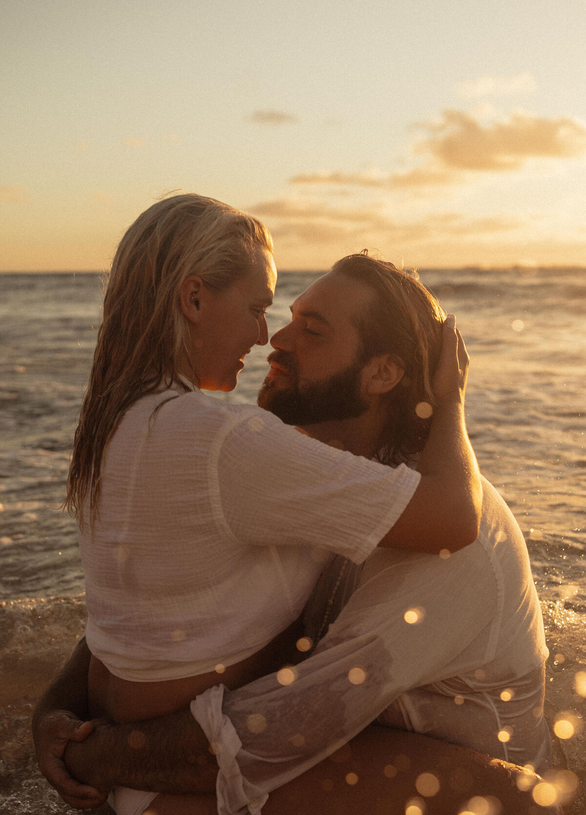 elopement couple embraces as they swim in the ocean under the orange sunset sky