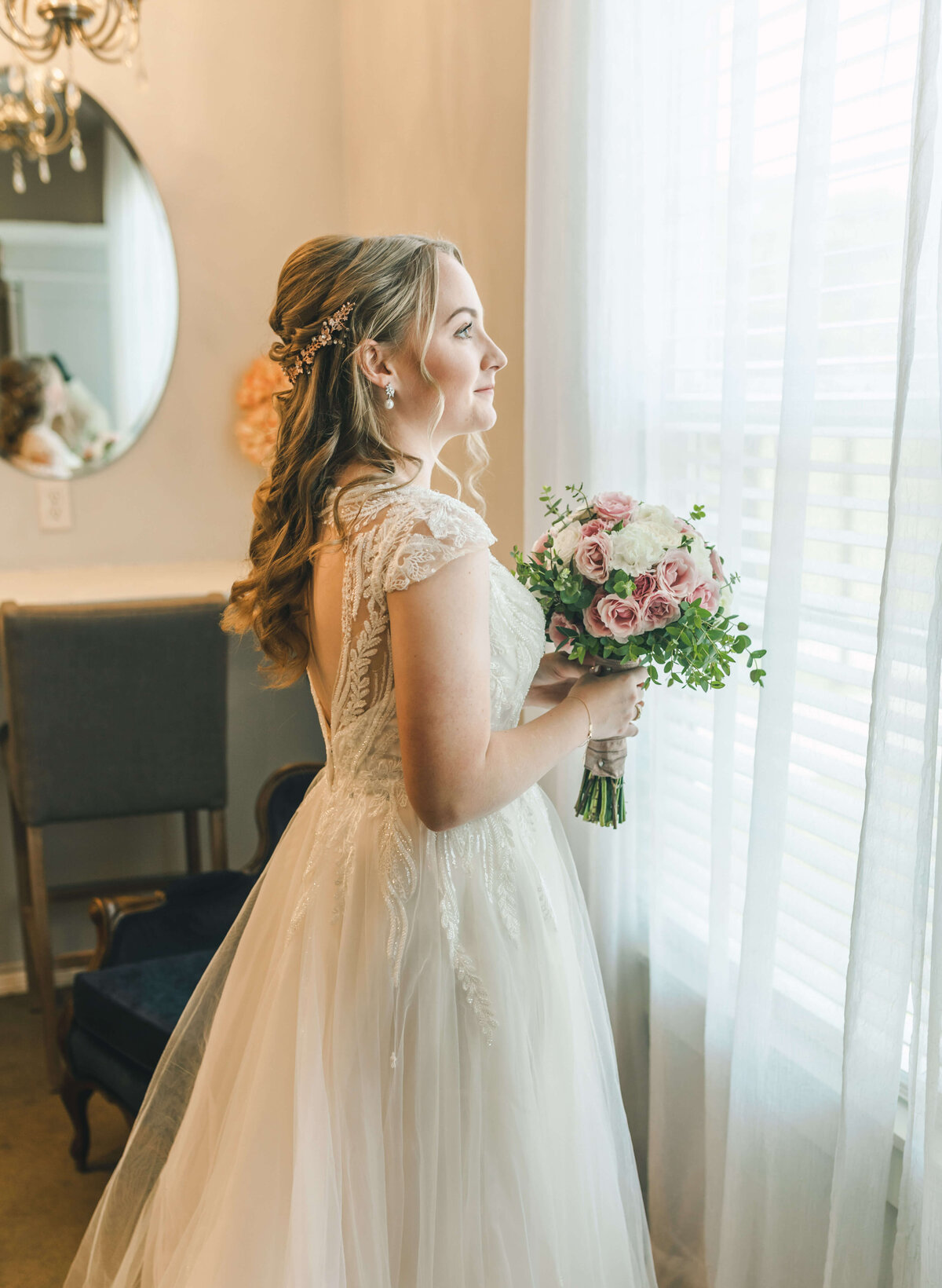 bride holds pink & white bouquet near window before intimate wedding