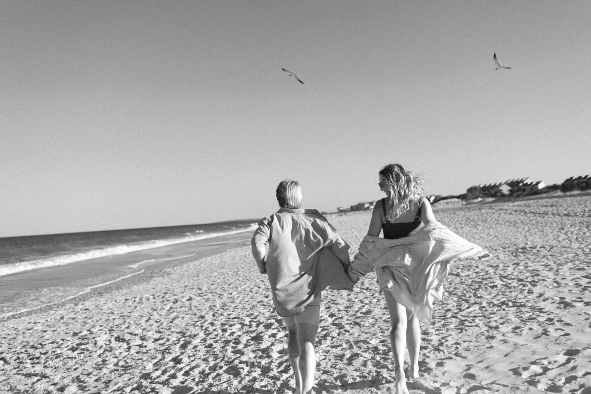 couple-running-on-beach-with-seagulls