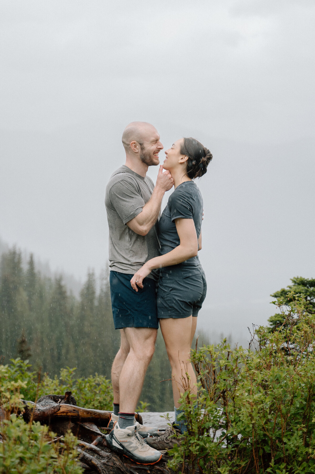 couple caught in the rain after a proposal session on big beehive hike at Lake Louise. 