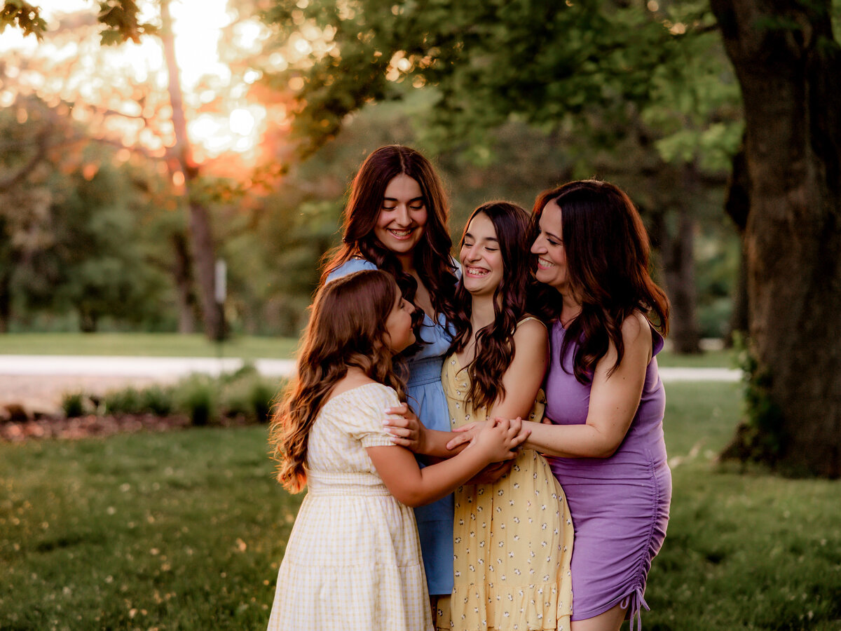 A mom and her daughters hug and laugh.