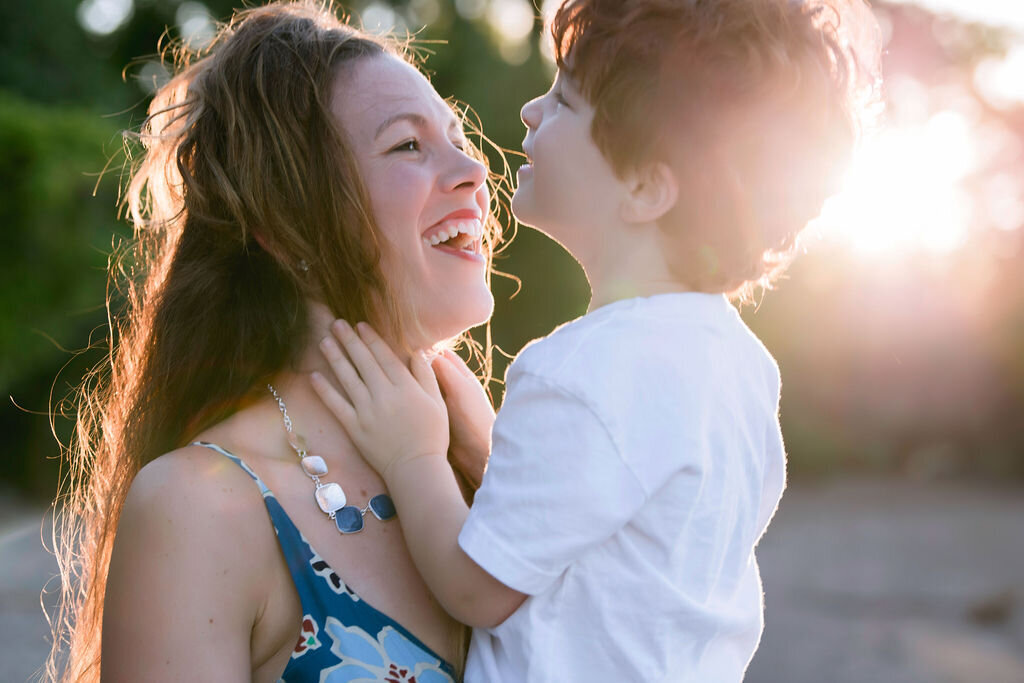 Mother and son laugh together with sunlight shining down on them