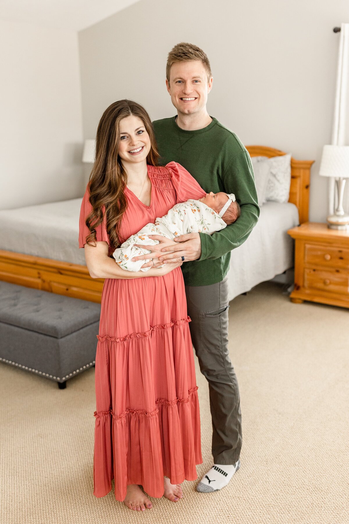 parents holding their newborn baby in a bedroom