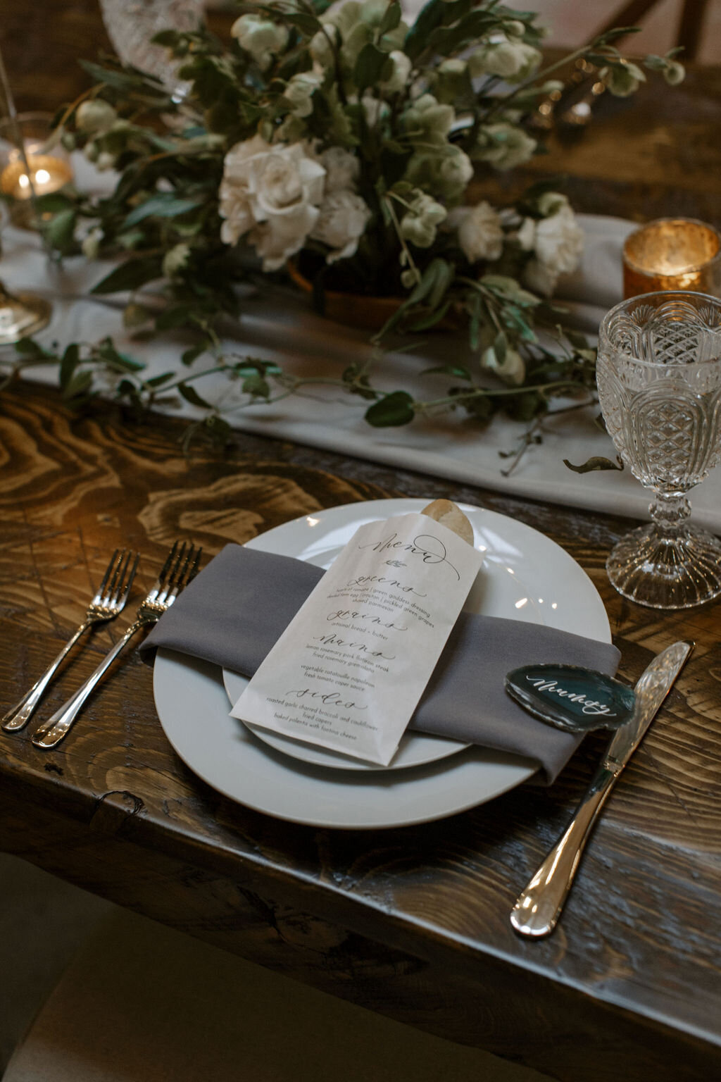 Gray napkins and white plates with greenery for romantic wedding reception