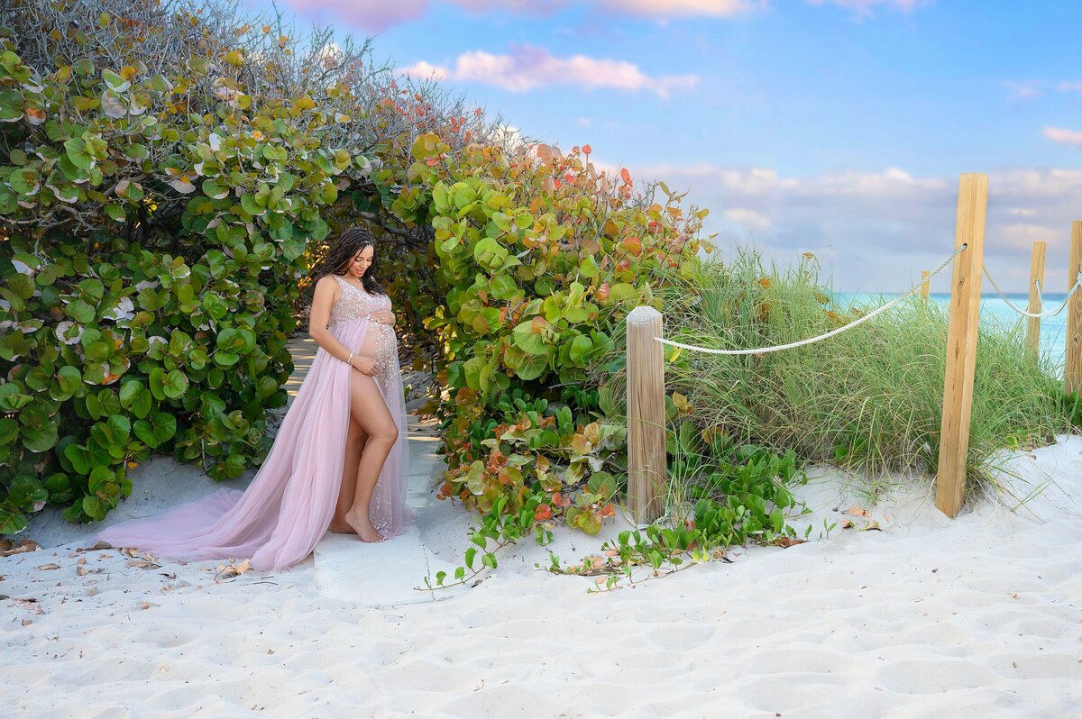 Expecting mom in pink dress for maternity pictures by the ocean in South Florida.