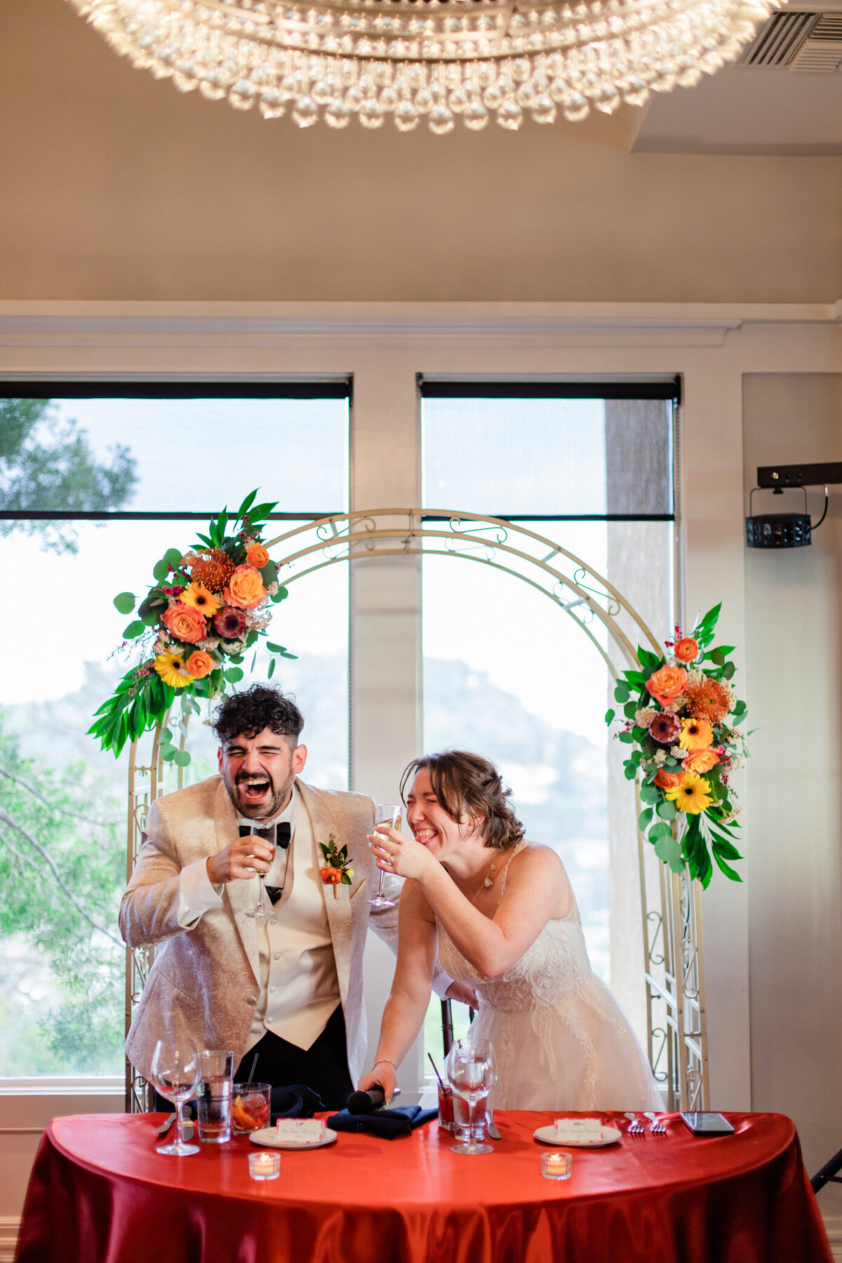 bride and groom laugh holding signature drinks