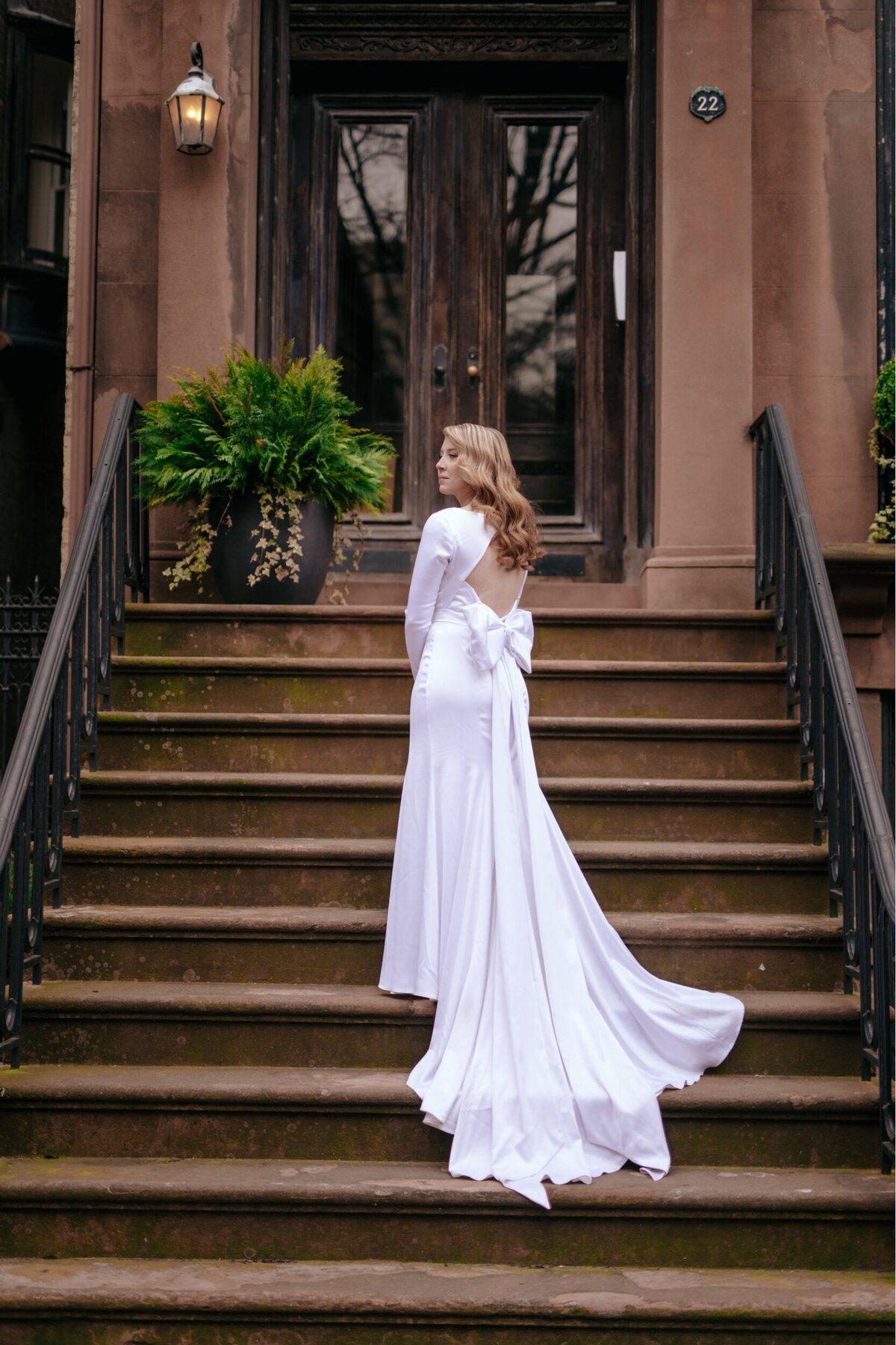 Bride in wedding dress on the stairs with the back view of her gown.