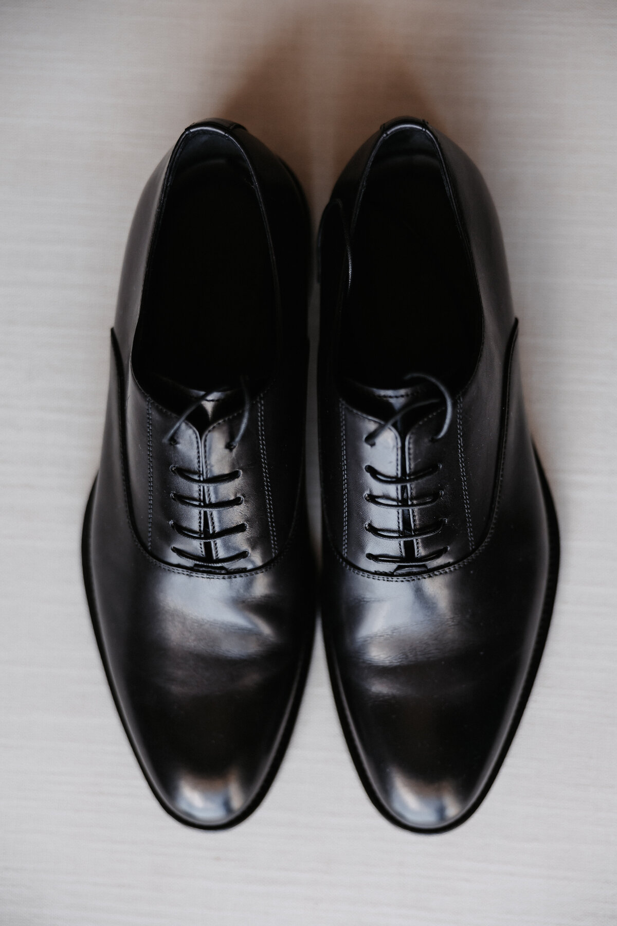 Black dress shoes laid flat on a neutral backdrop
