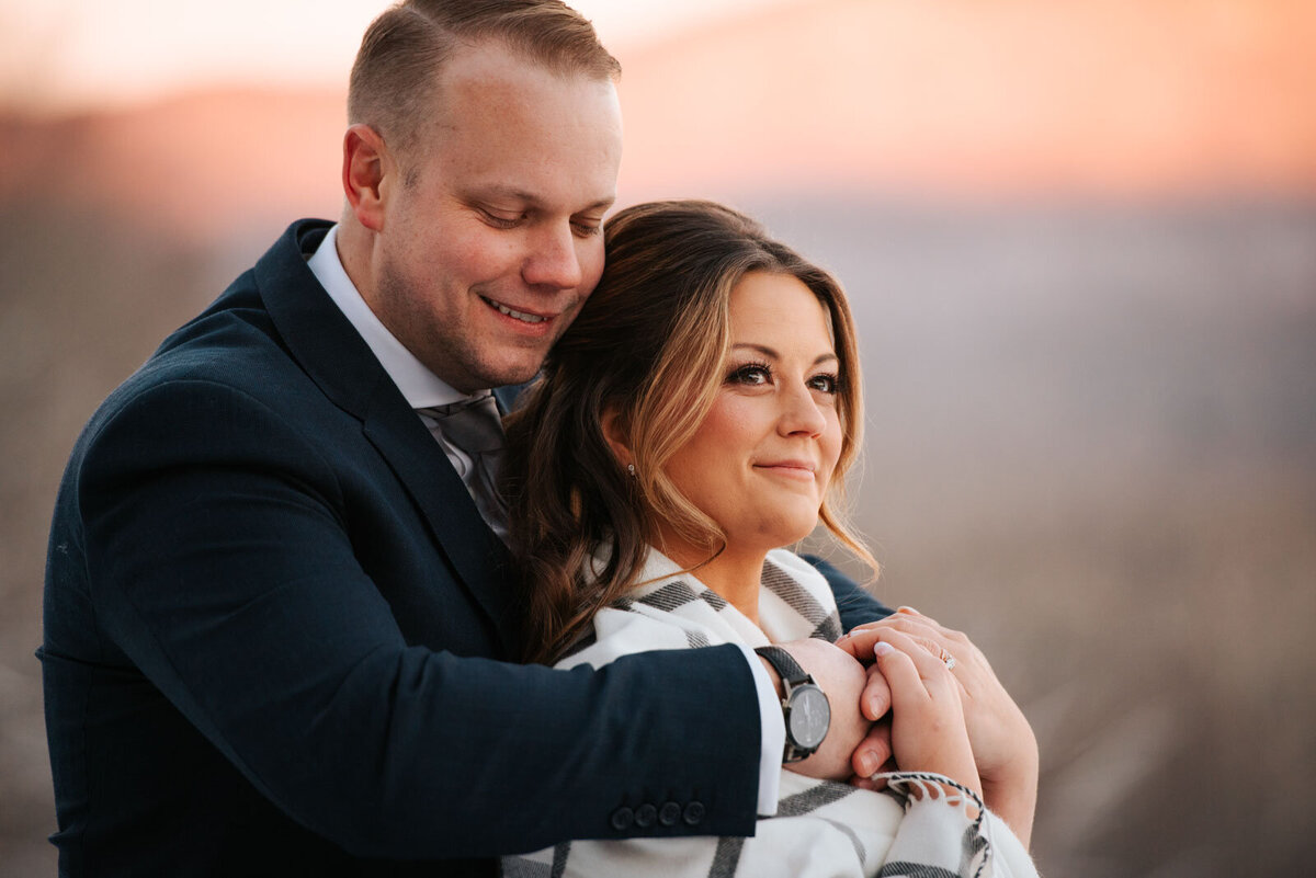 bride and groom cuddled in blanket at pink sunset mountain top inn wedding vermont