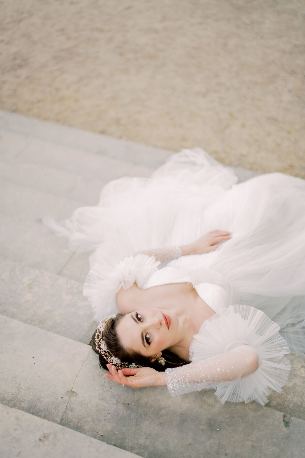 Bride is lying down on stairs and is looking into the camera in france