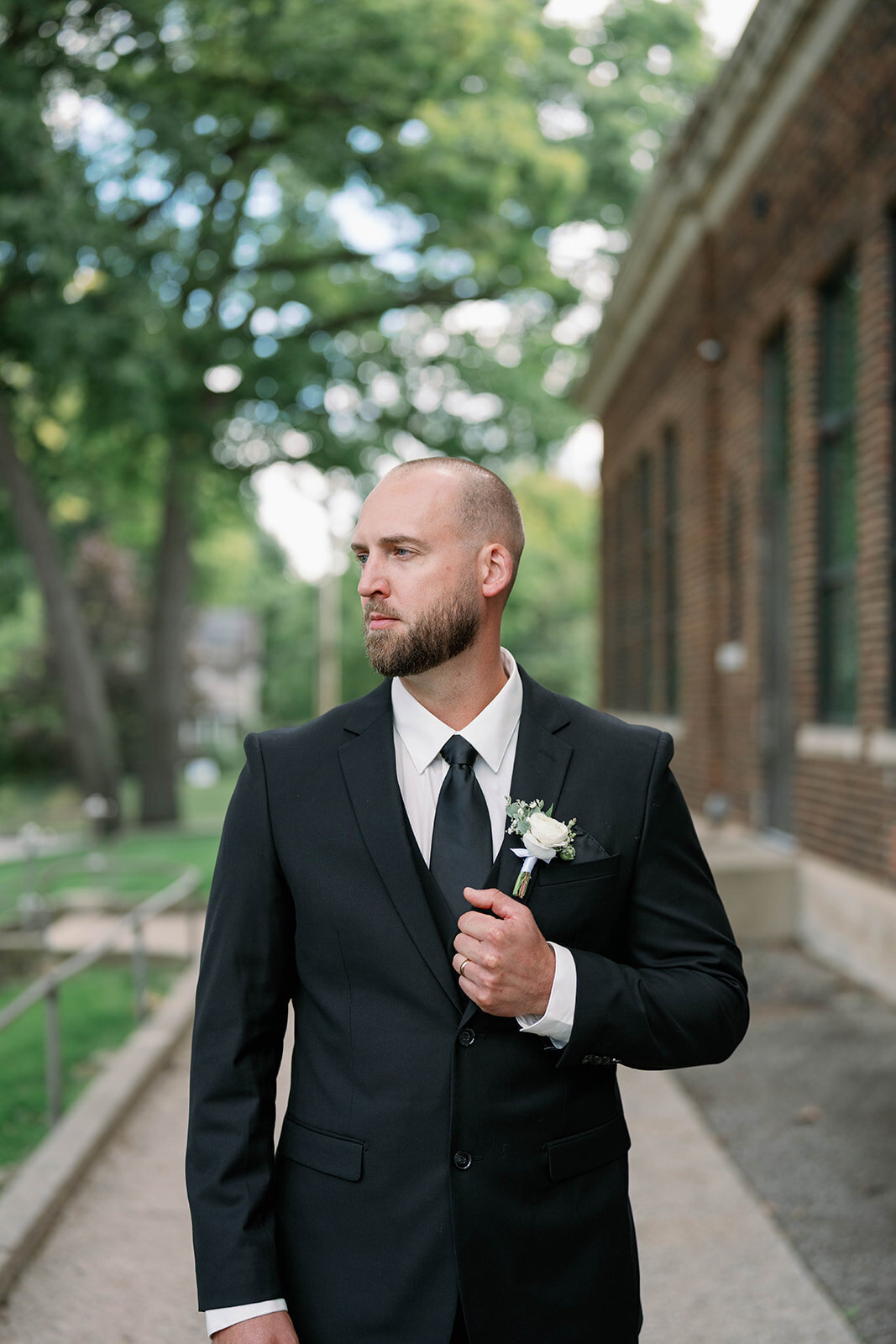 Portrait of the groom adjusting his jacket during bridal party portraits at Leona Road Wedding Venue in Grand Rapids MI.