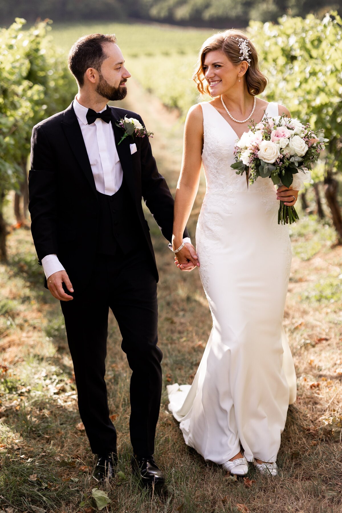 Wedding photography of bride and groom walking holding hands in vineyards at Denbies in Surrey