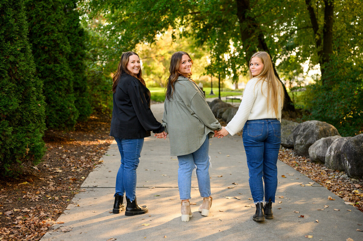 A heartwarming photo of three friends walking hand-in-hand on a scenic path, captured by Leslie Q Photography