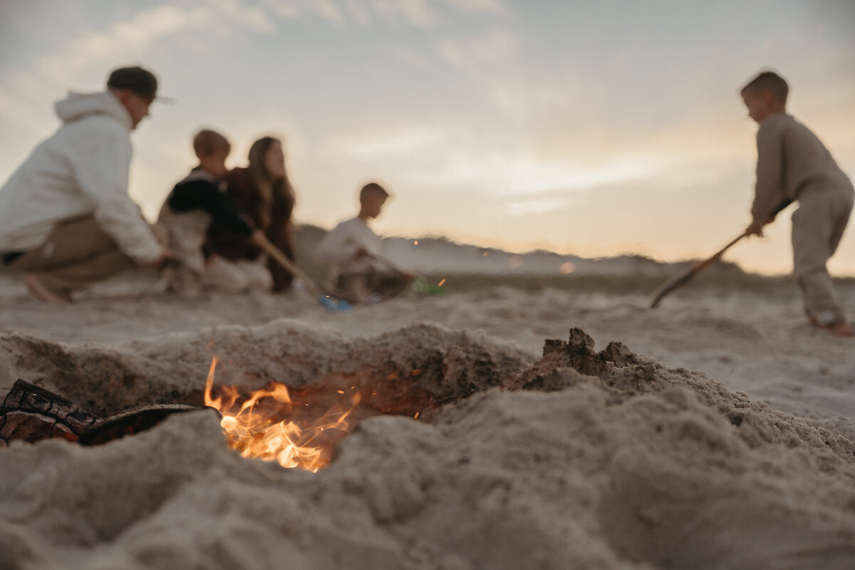 Family sitting around a beach bonfire roasting marshmallows 