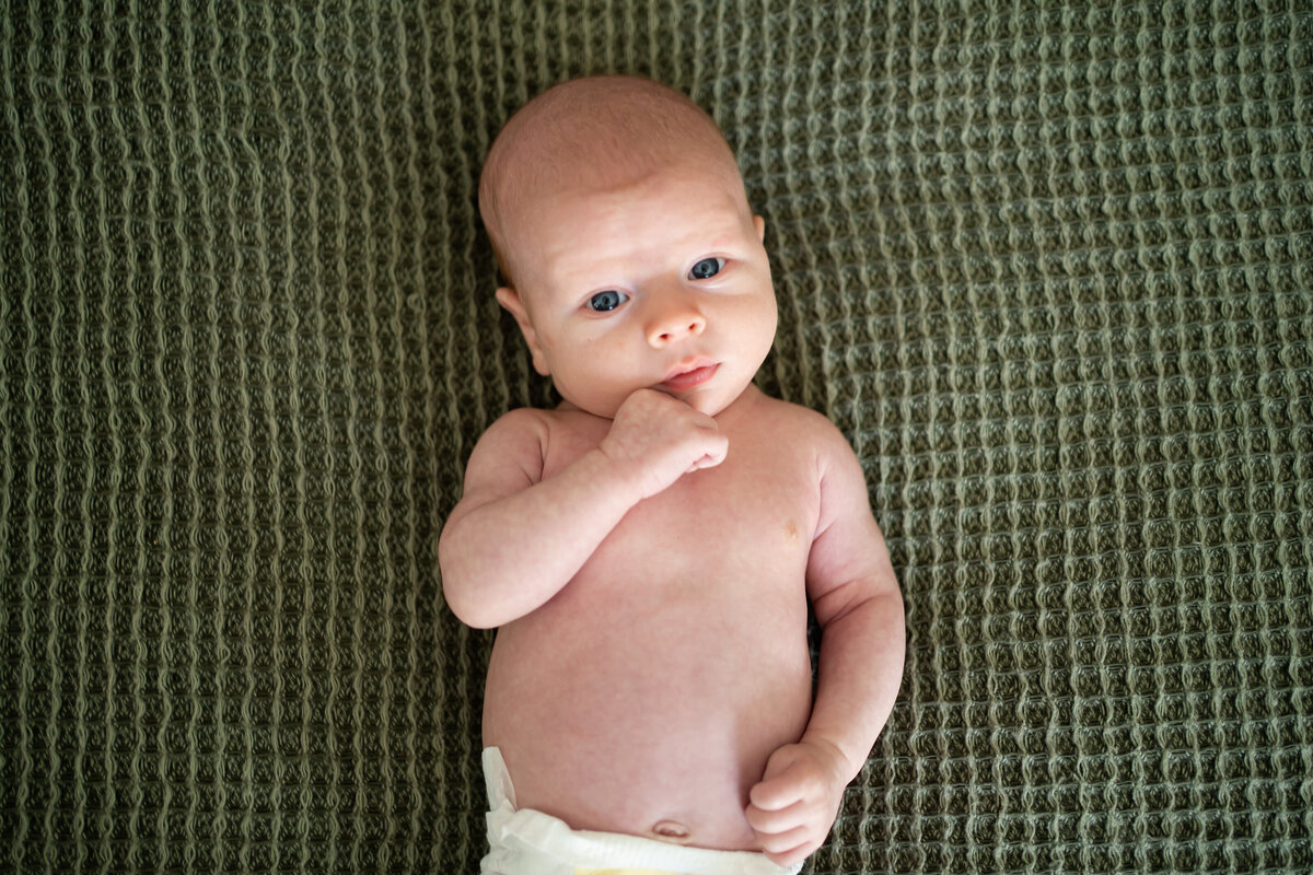 Baby laying on his back on green blanket