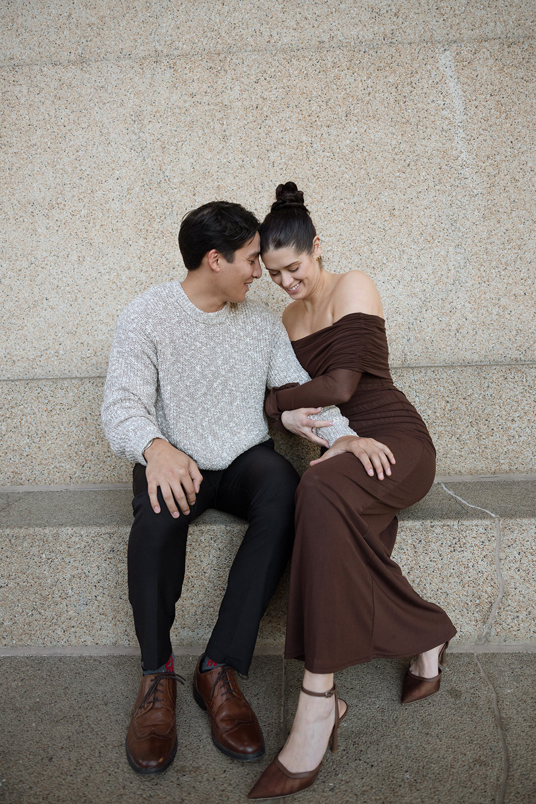 Couple snuggles close together joyfully after getting engaged. 
