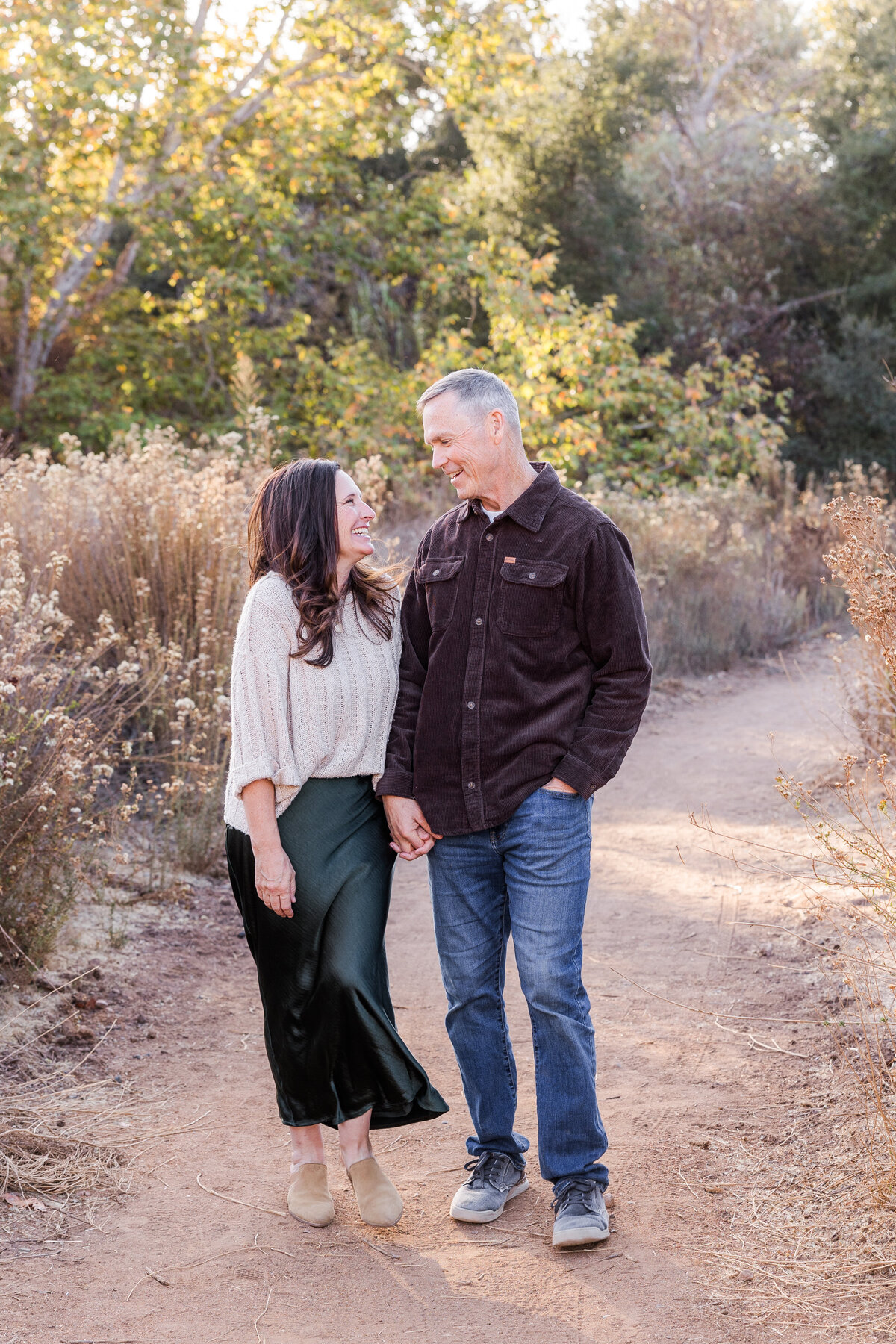 parents walking down dirt path holding hands