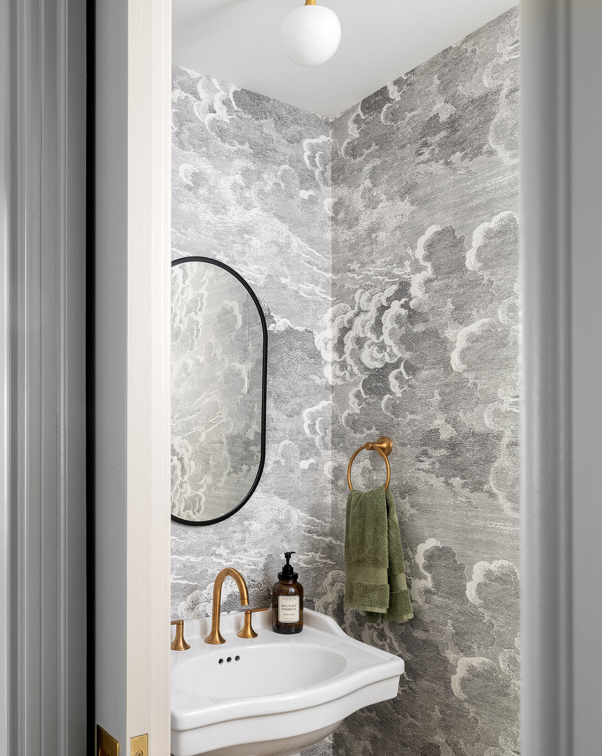 open door to gray marble powder room with gold accent