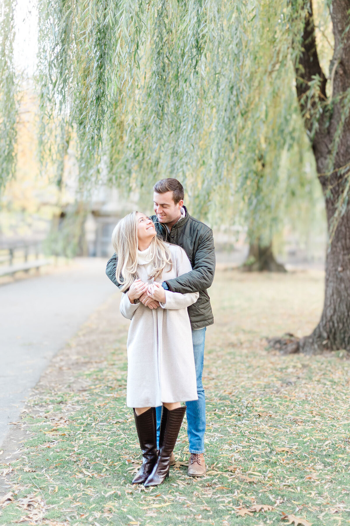 A man hugs his fiancee from behind as the bride to be looks up at him