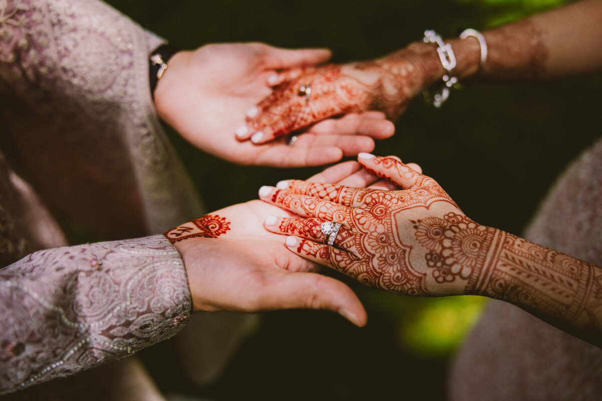 Indian bride and groom holding hands with henna on them on the wedding day