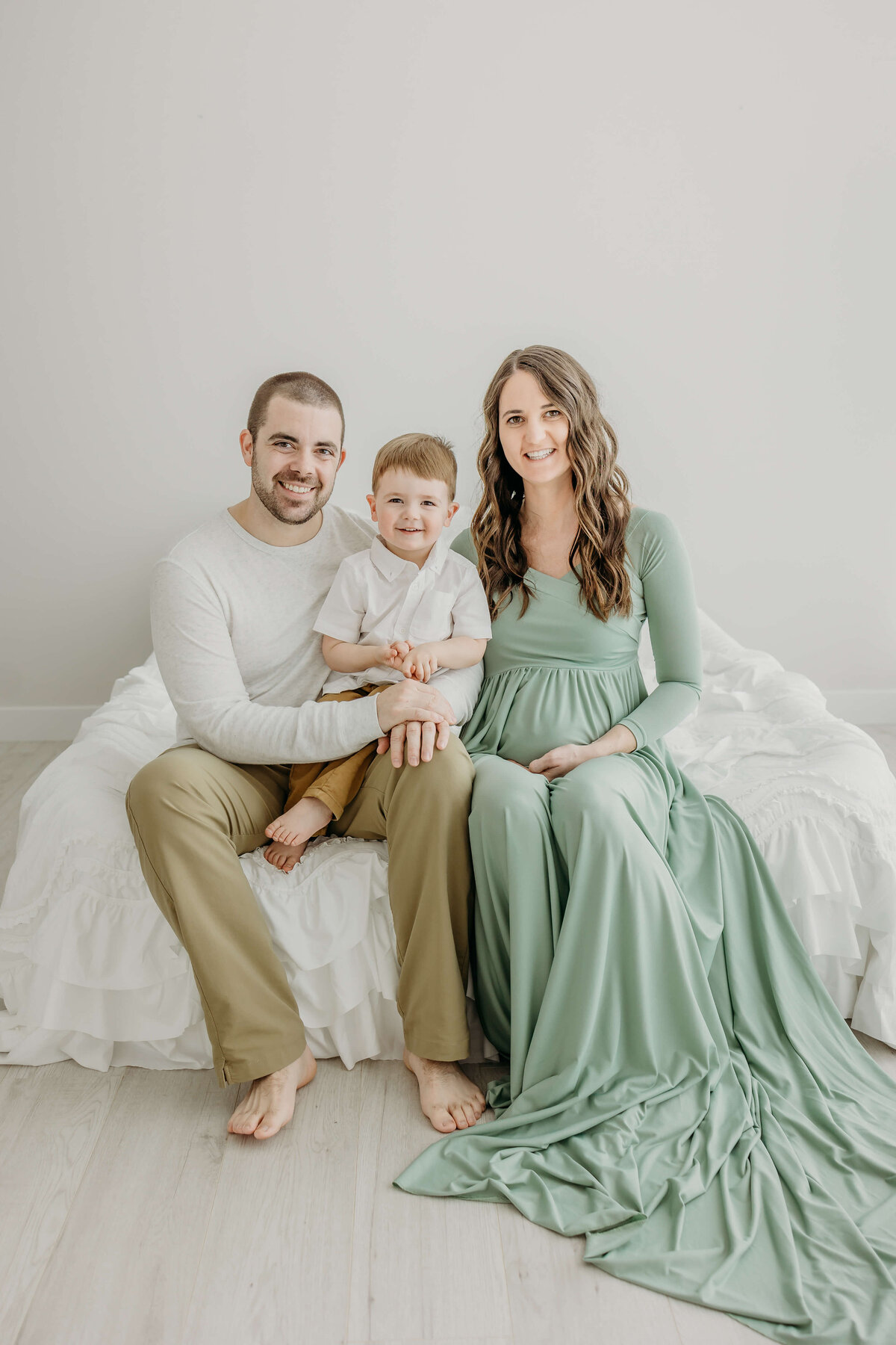 Family portrait of young couple and son sitting on bed