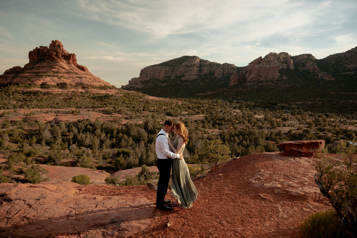 Couple standing against red rock backdrop during Sedona engagement session
