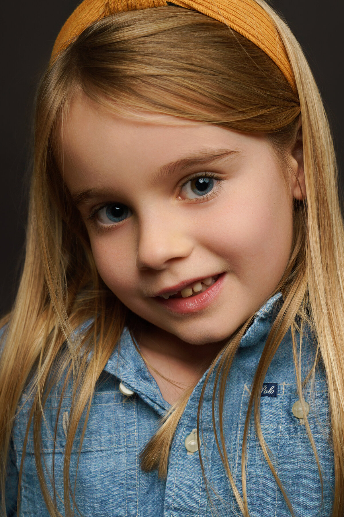 Extreme Closeup portrait of young girl wearing denim Ralph Lauren Polo Dress with blonde hair and blue eyes