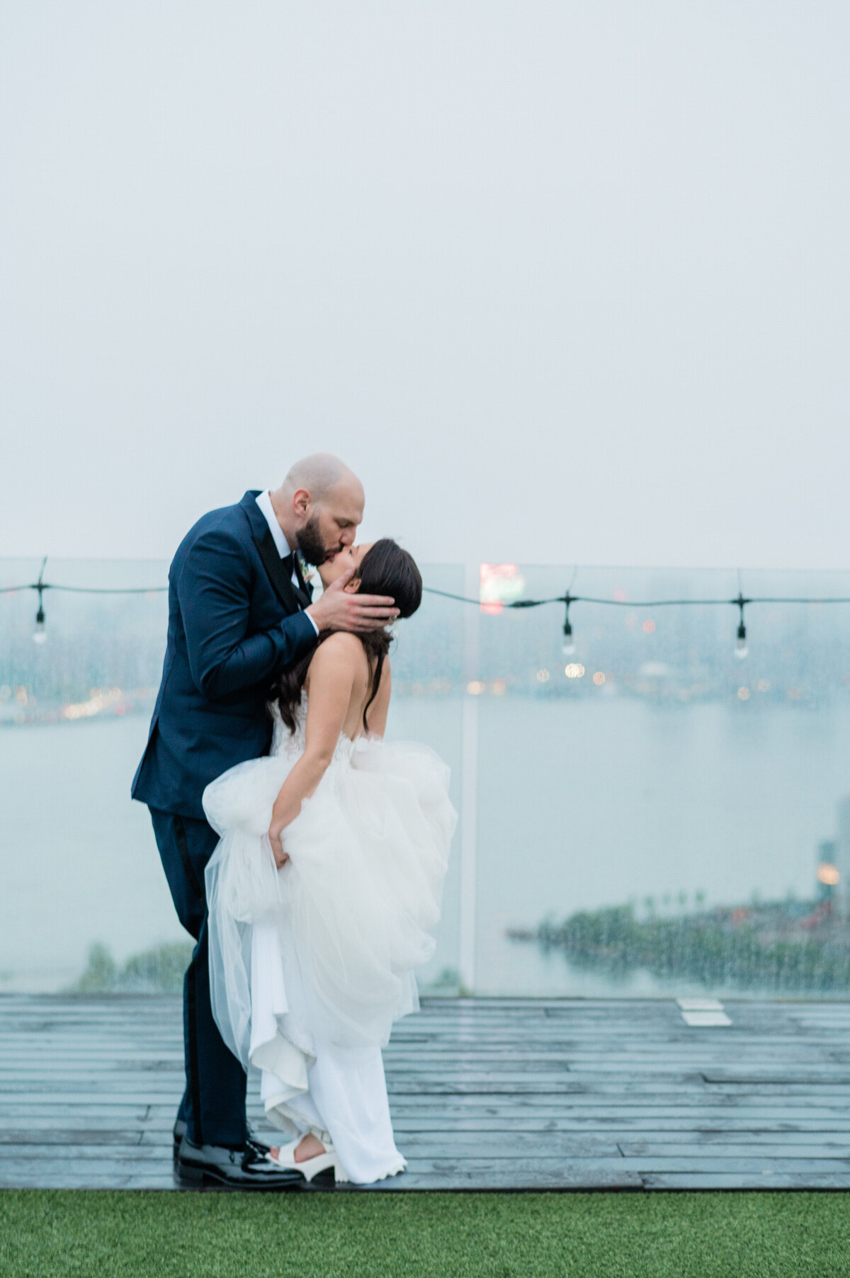 Newlyweds kiss on the rainy rooftop of William Vale 