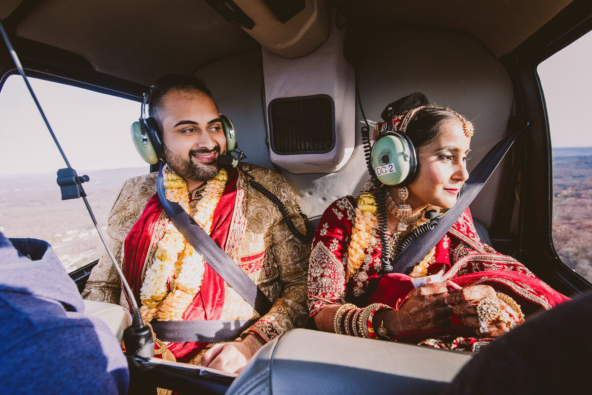 Indian bride and groom in the backseat of a helicopter enjoying the view after their hindu ceremony in connecticut