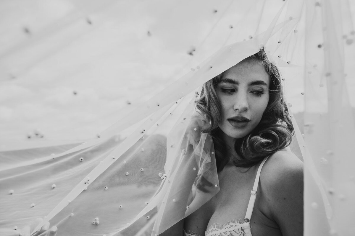 Wedding Photographer, a bride stands beneath her veil as it lifts in the wind