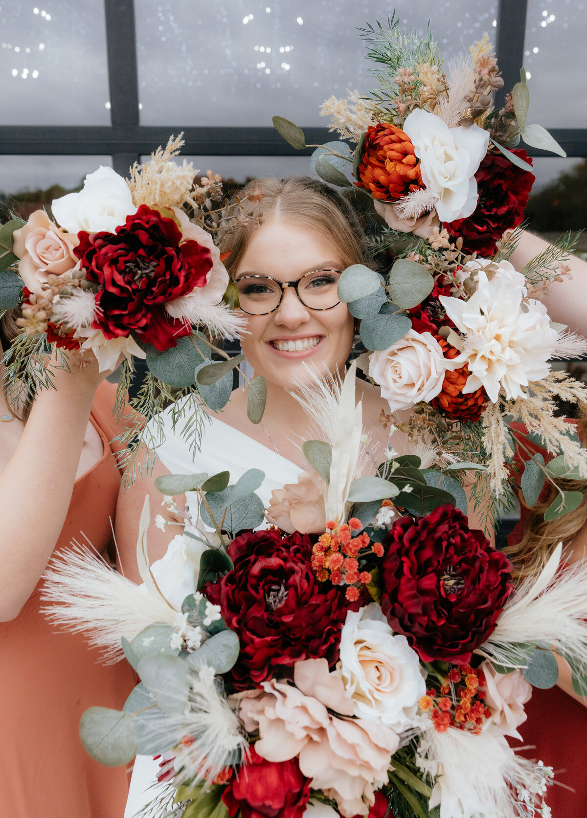 The bride is posing with a crown of bouquets around her face. 