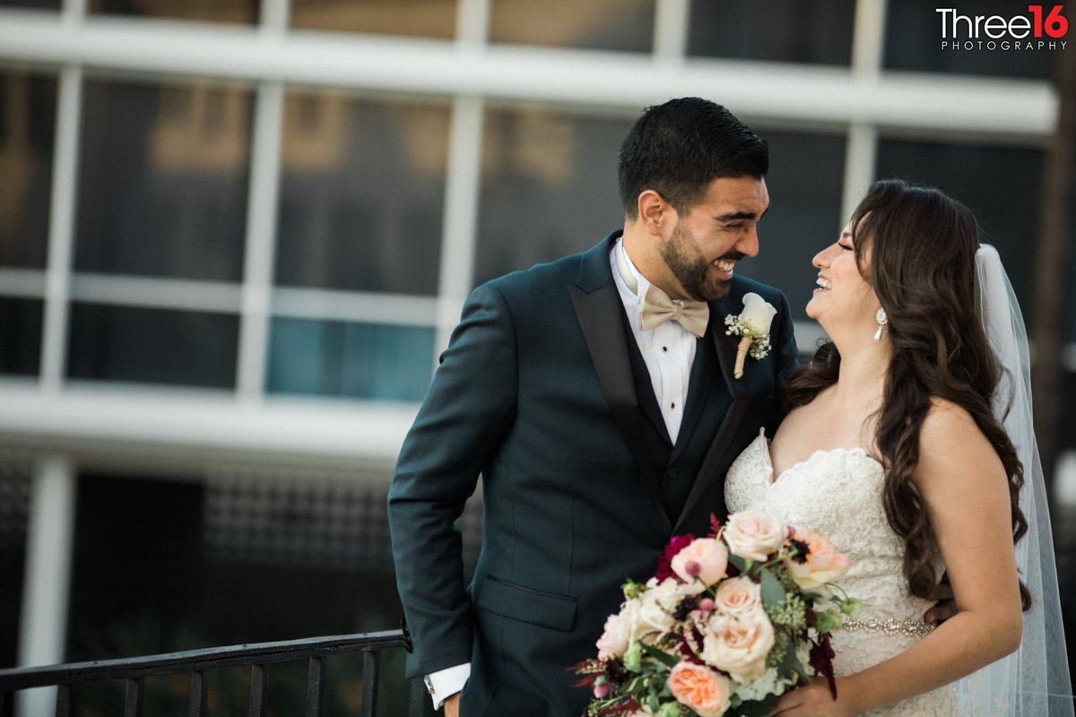 Bride and Groom laugh as they  look into each other's eyes during photo shoot