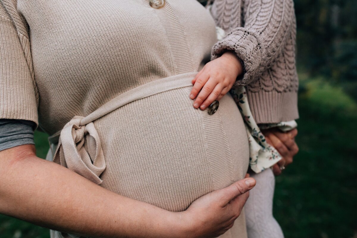 toddler touching mum's pregnant belly during outdoor maternity photography session
