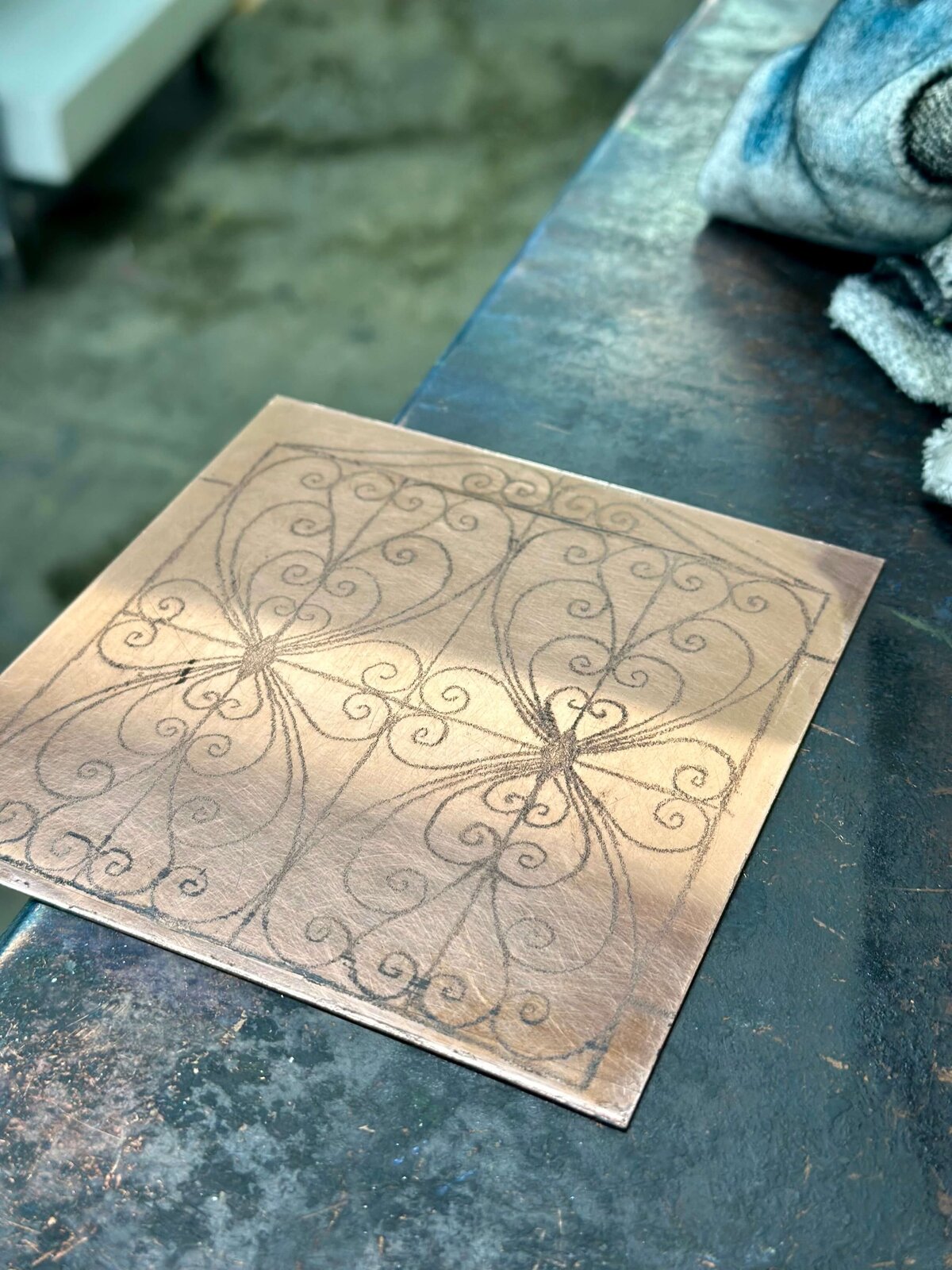 Close-up of a clean copper plate etched with detailed symmetrical linework, capturing the drawing stage before aquatint.