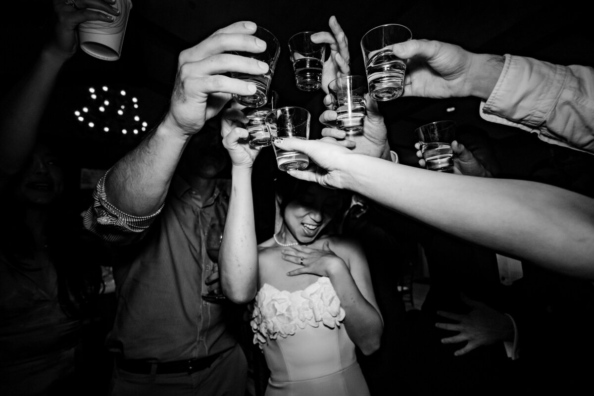 Black and white photo of a bride clinking her cocktail glass with her guests on the dancefloor at a wedding ceremony in Santa Monica, photo by Tanya Parada